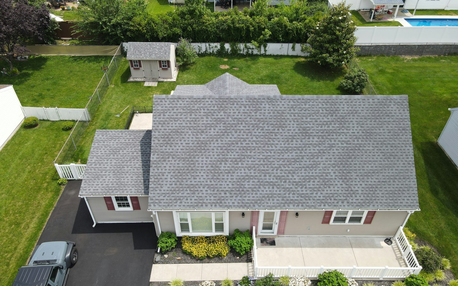 Aerial view of a suburban home with a shingle roof and green lawn